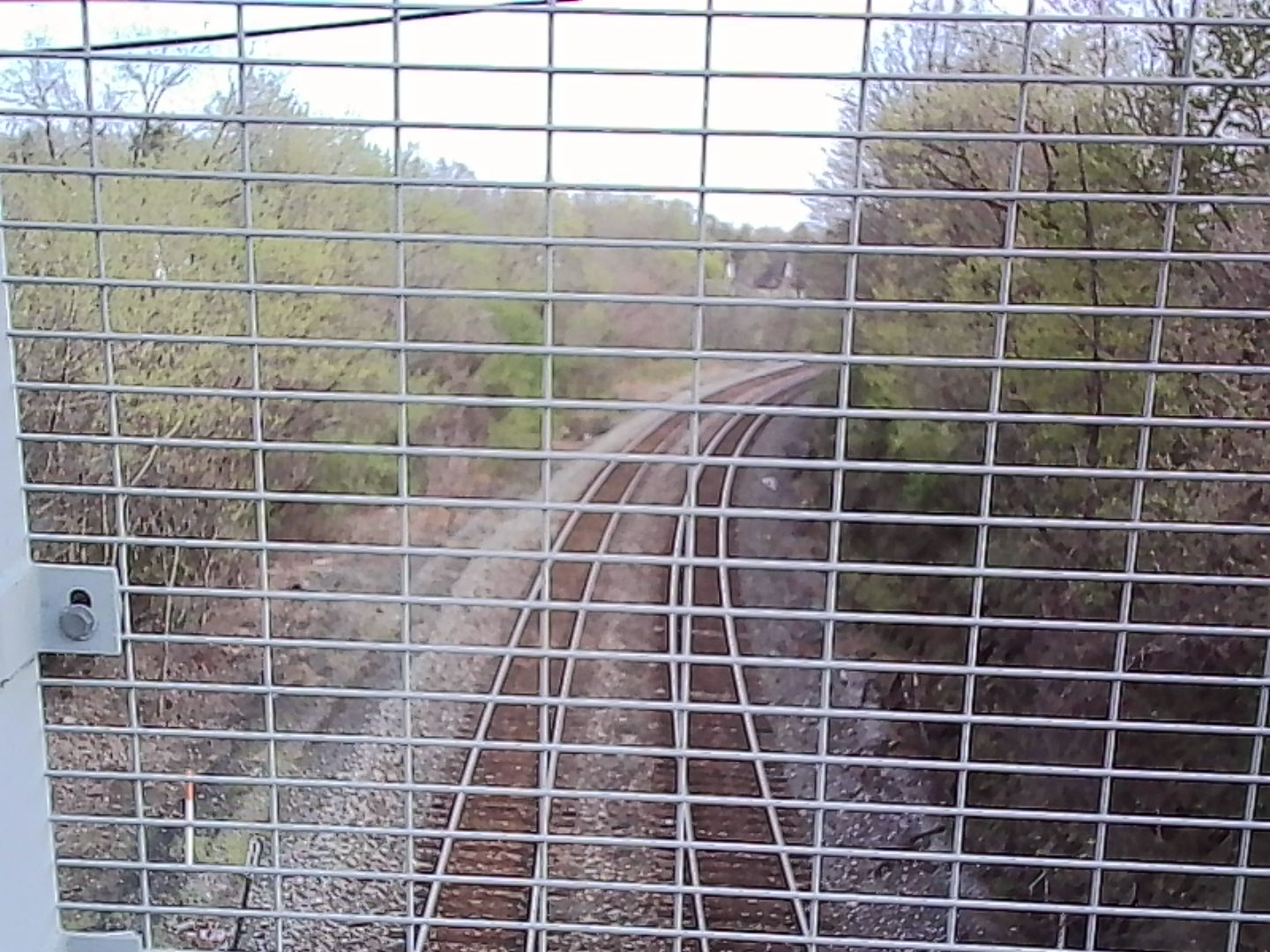 Train tracks as viewed through the fence on a different bridge
